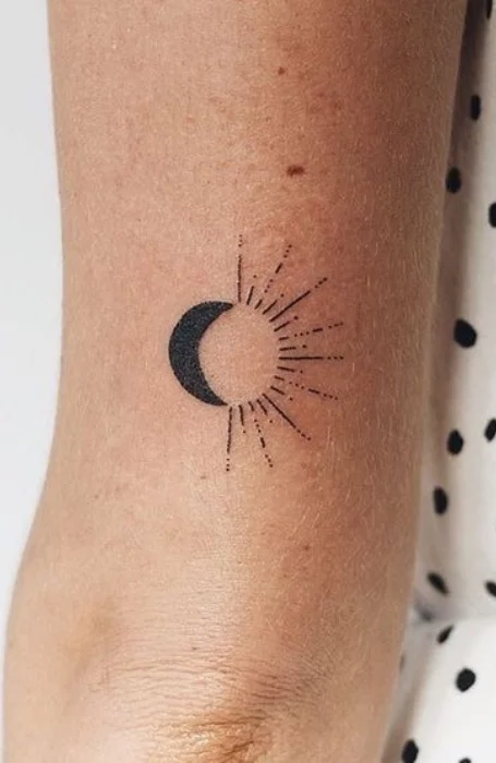 Half sun and crescent moon tattoo with radiant sun rays on the arm