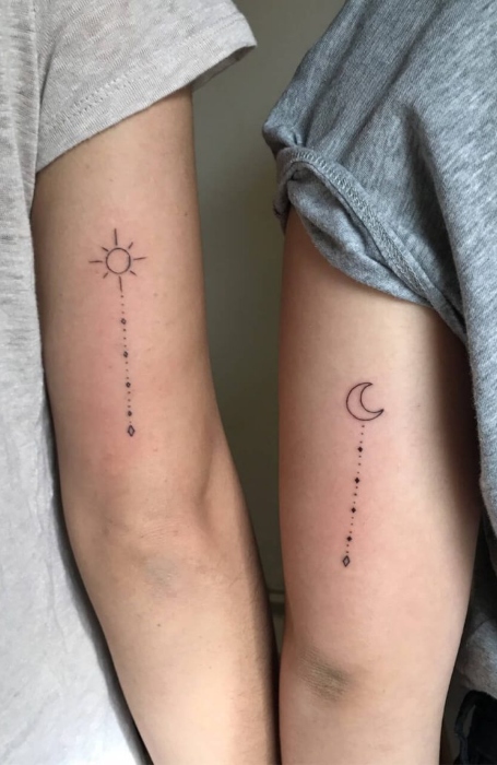 Minimalist matching sun and crescent moon tattoos on the upper arms of two individuals