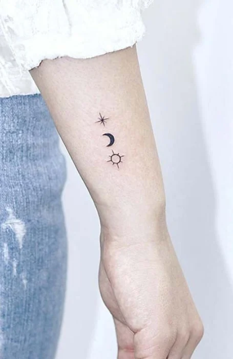 Minimal sun, moon, and star tattoo design on the inner forearm