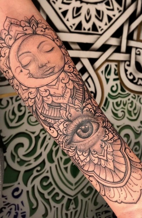 Detailed sun and moon tattoo with all-seeing eye and ornamental patterns on forearm