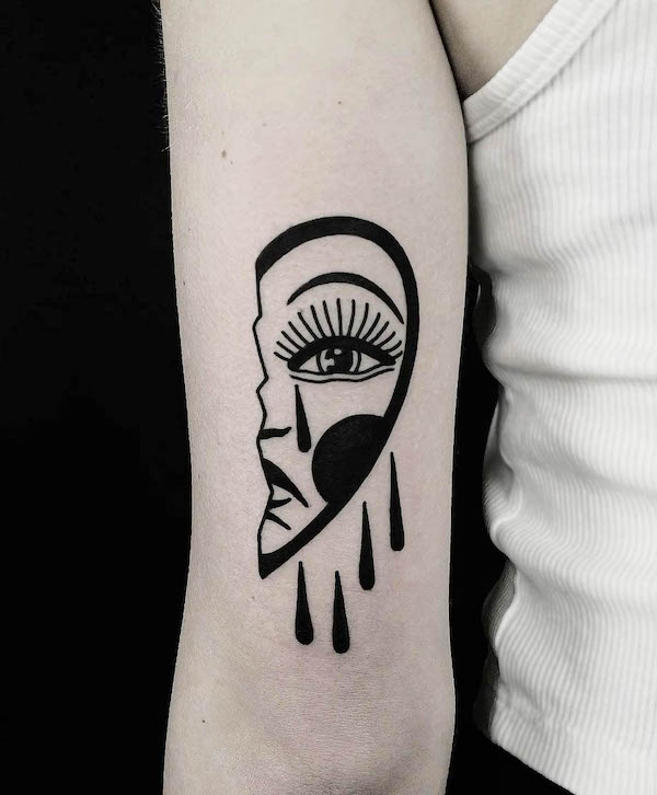 Abstract face tattoo with teardrops in bold black ink on forearm