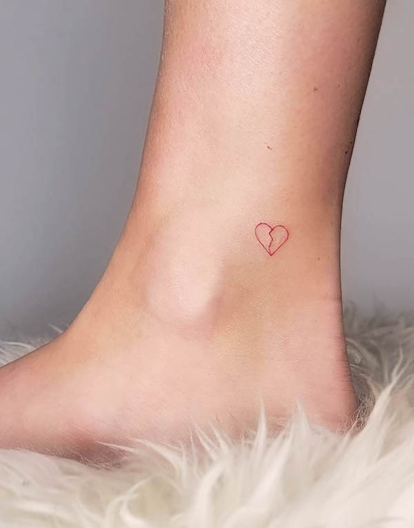 Small red broken heart tattoo on ankle symbolizing heartbreak or emotional healing.