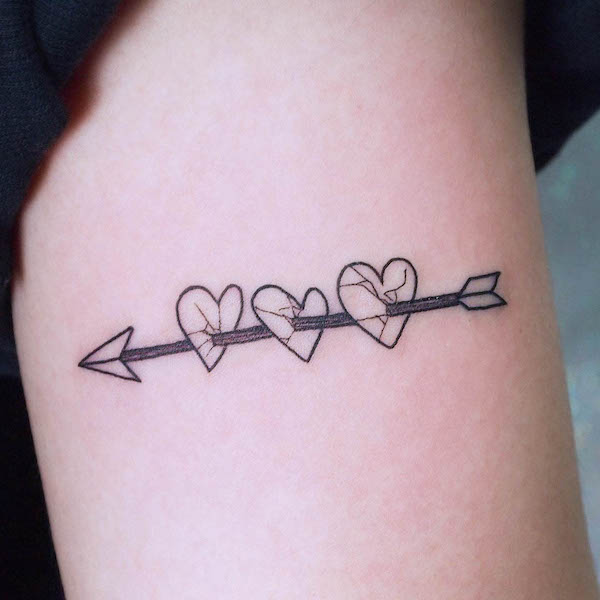 Minimalist tattoo of three hearts pierced by a black arrow