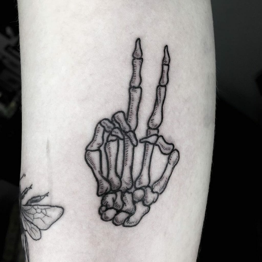 Skeleton hand tattoo with a middle finger gesture drawn in bold black ink outline