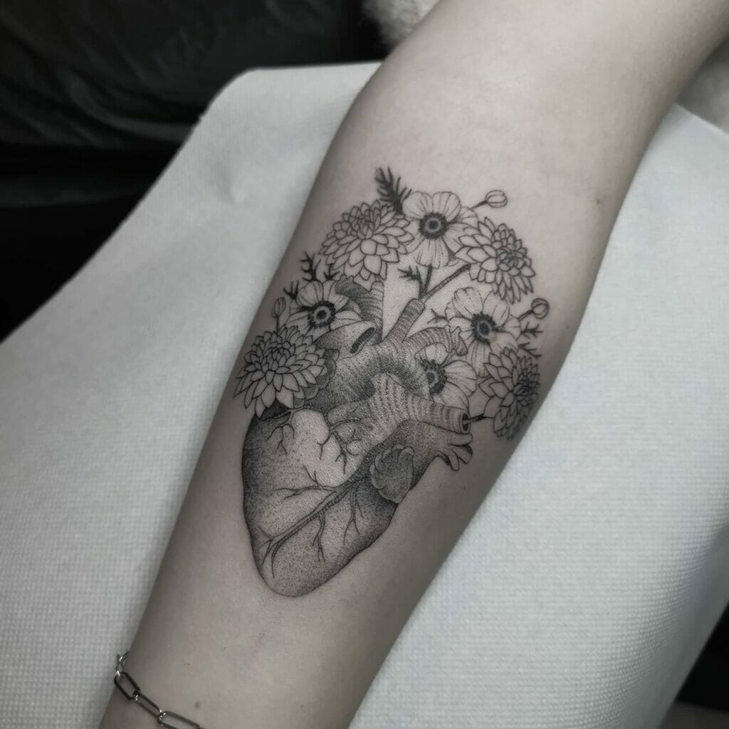 Floral anatomical heart tattoo with black and gray shading on forearm