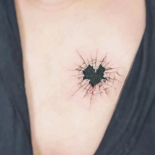 Cracked black heart tattoo with realistic crack effects on chest