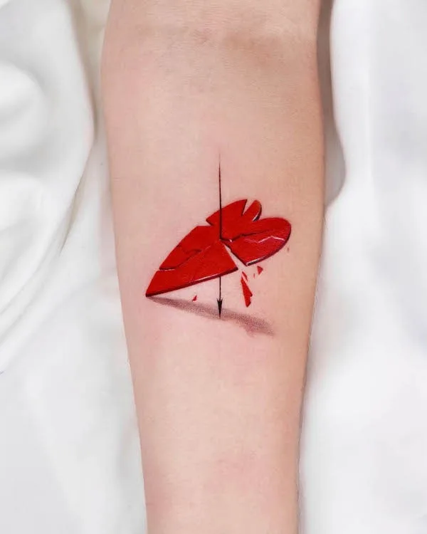 Shattered red heart tattoo with arrow piercing through on forearm