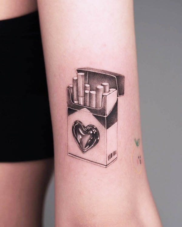 Cigarette pack tattoo with heart design and realistic shading on forearm