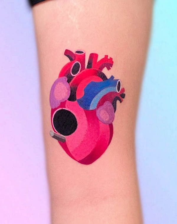 Colorful geometric anatomical heart tattoo in red, pink, blue, and purple on arm