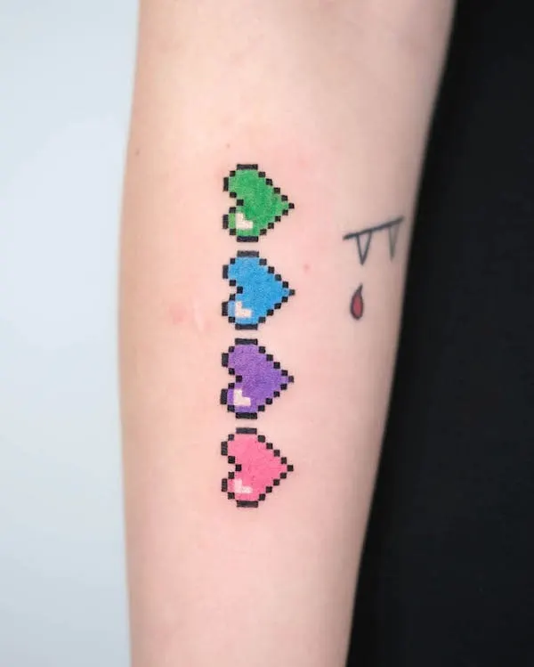 Pixelated hearts tattoo in green, blue, purple, and pink resembling retro video game life icons