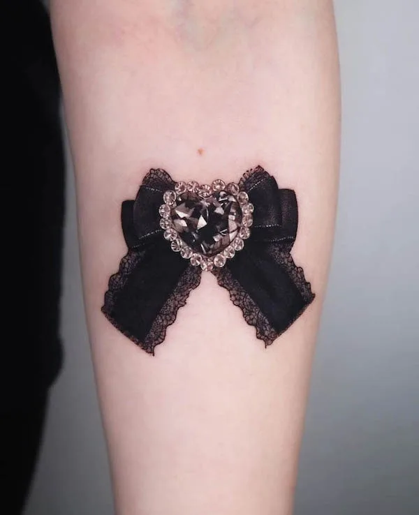 Elegant heart-shaped gem tattoo with lace-trimmed black bow symbolizing love and beauty