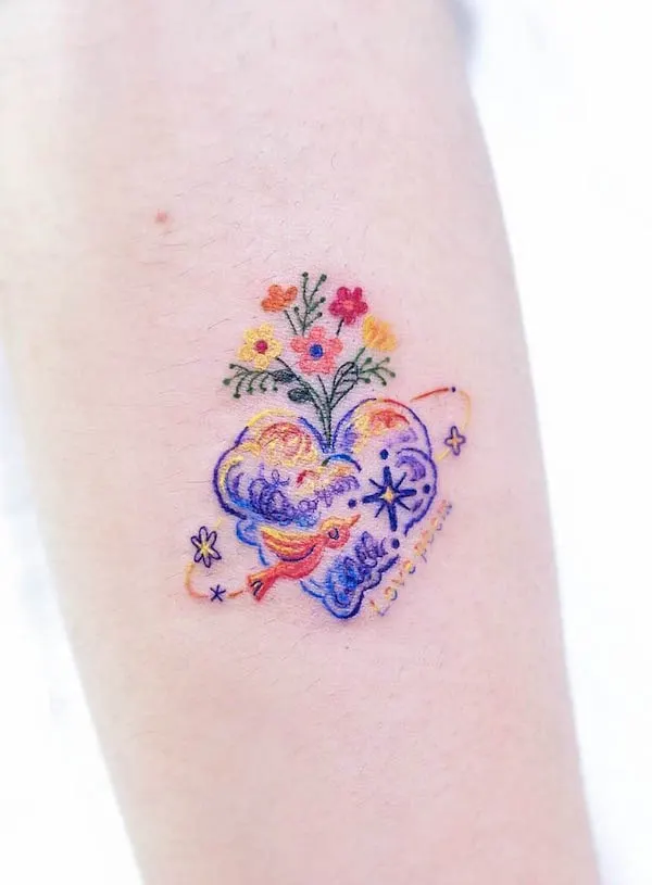 Whimsical floral bird heart tattoo with colorful flowers, bird, and celestial elements