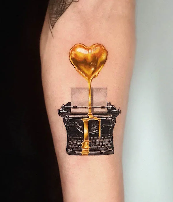 Typewriter tattoo with golden heart and molten gold design on forearm