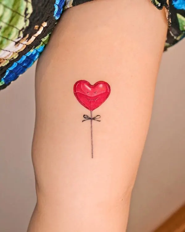 Red heart-shaped balloon tattoo with a bow string on the arm, symbolizing love, lightness, and joy