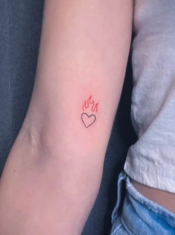 Minimalist heart tattoo with red flames above symbolizing passionate love and inner fire