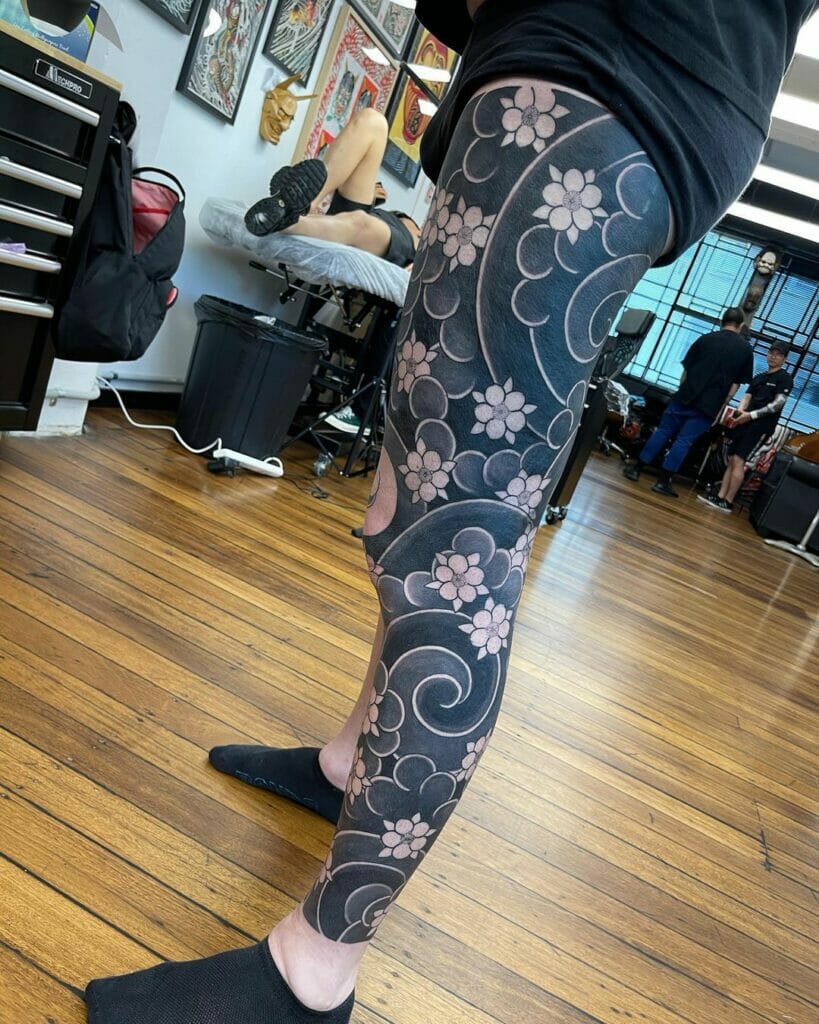 Japanese leg sleeve tattoo featuring black ink waves and pink cherry blossoms in a bold design