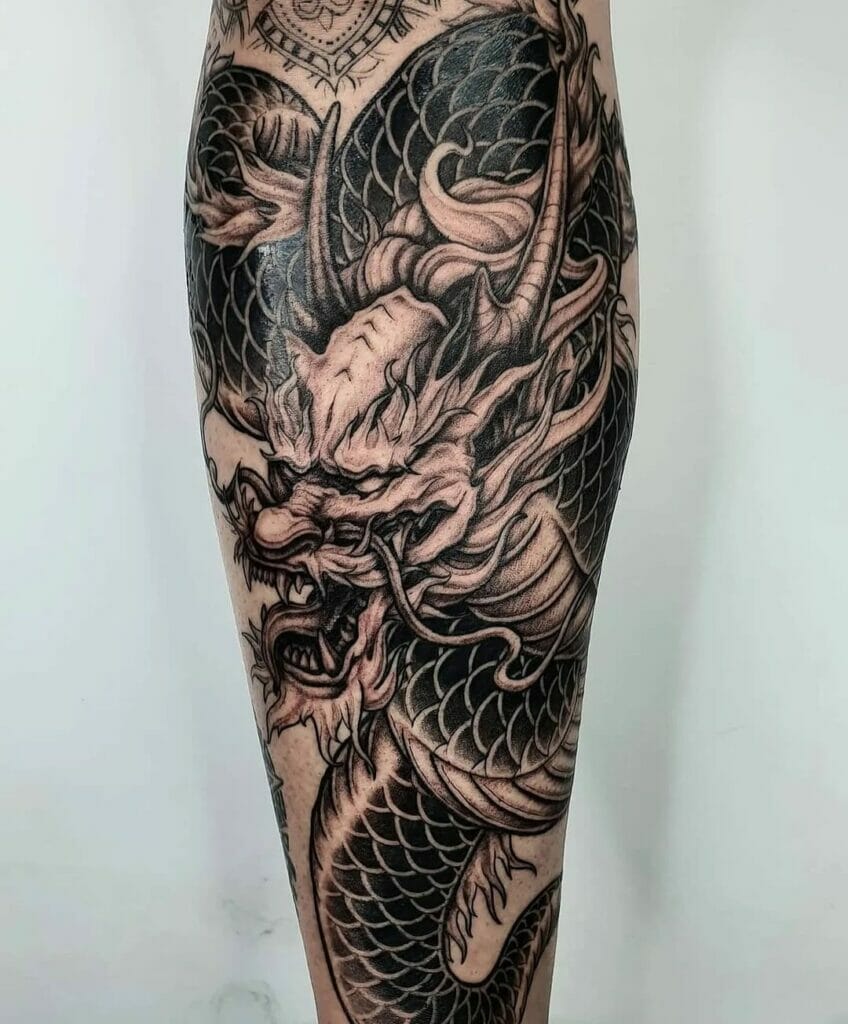 Traditional Japanese dragon leg tattoo with detailed black and gray scales and fierce facial features