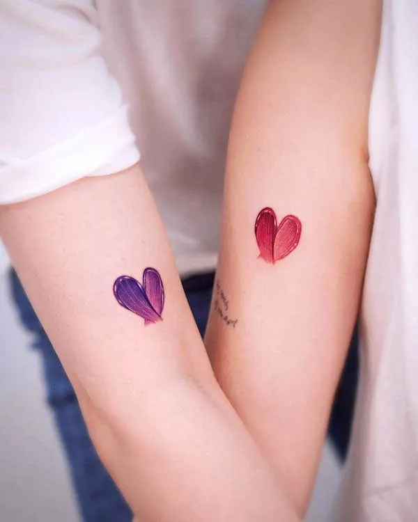 Matching purple and red heart tattoos with brushstroke texture symbolizing love, unity, and individuality