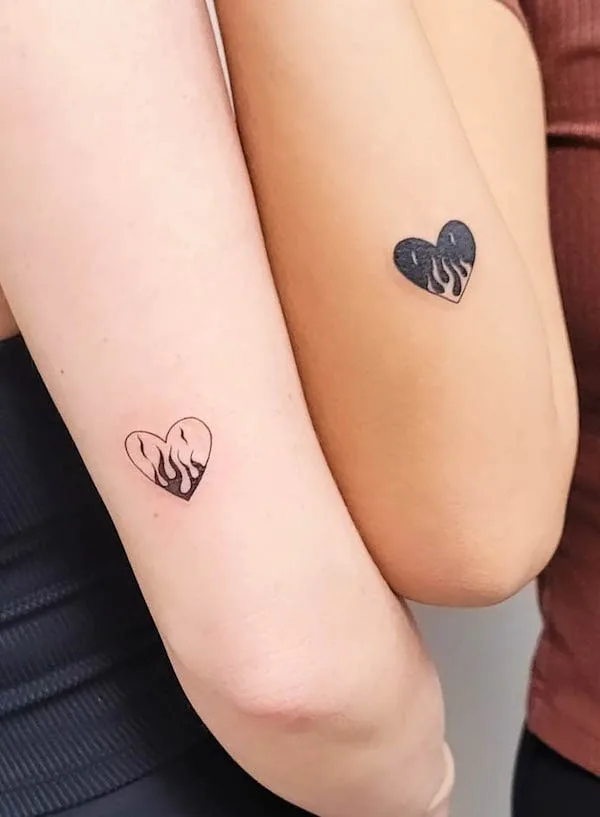 Matching flaming heart tattoos in black and light outline, symbolizing passionate love and connection