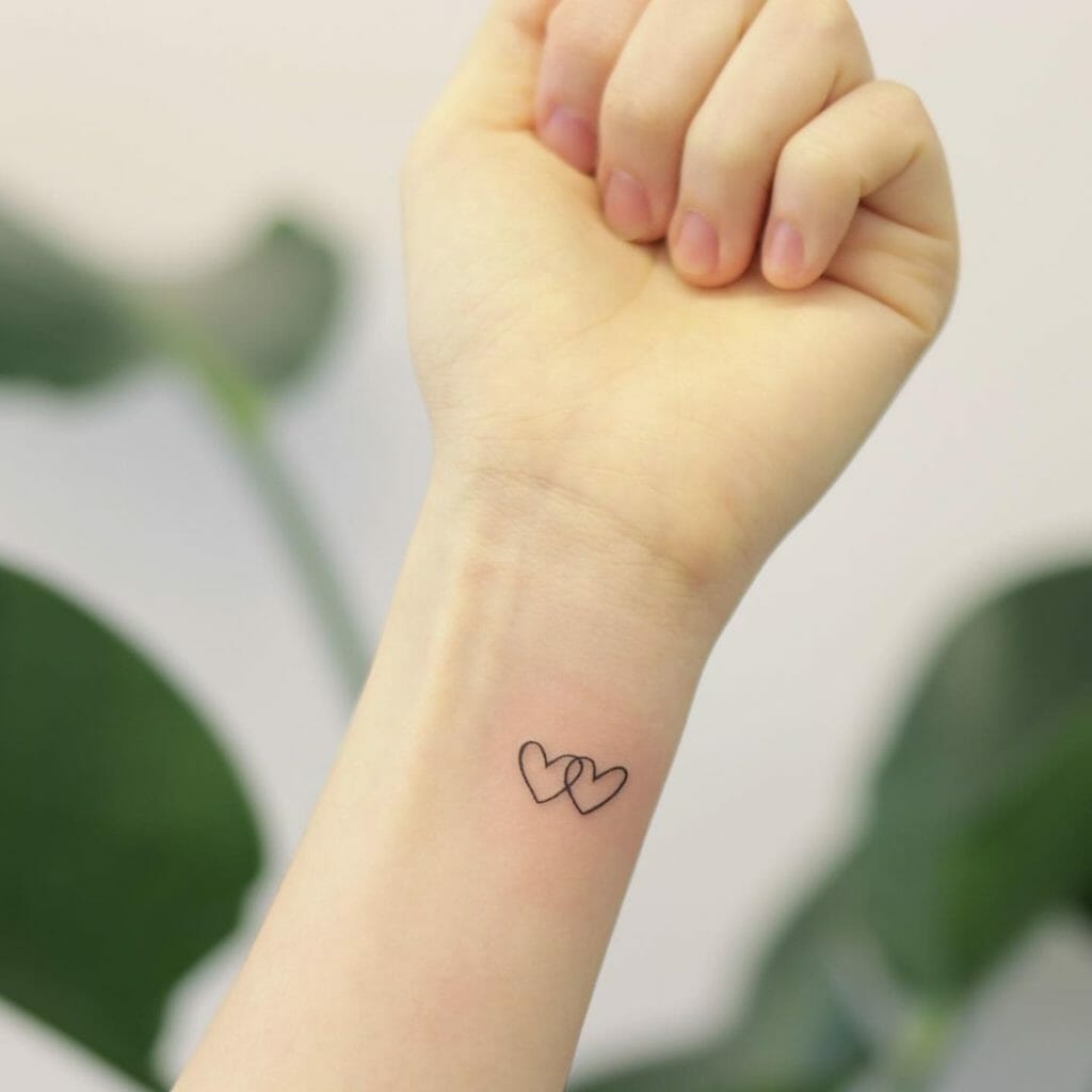 Minimalist interlocking hearts tattoo on inner wrist with fine black linework