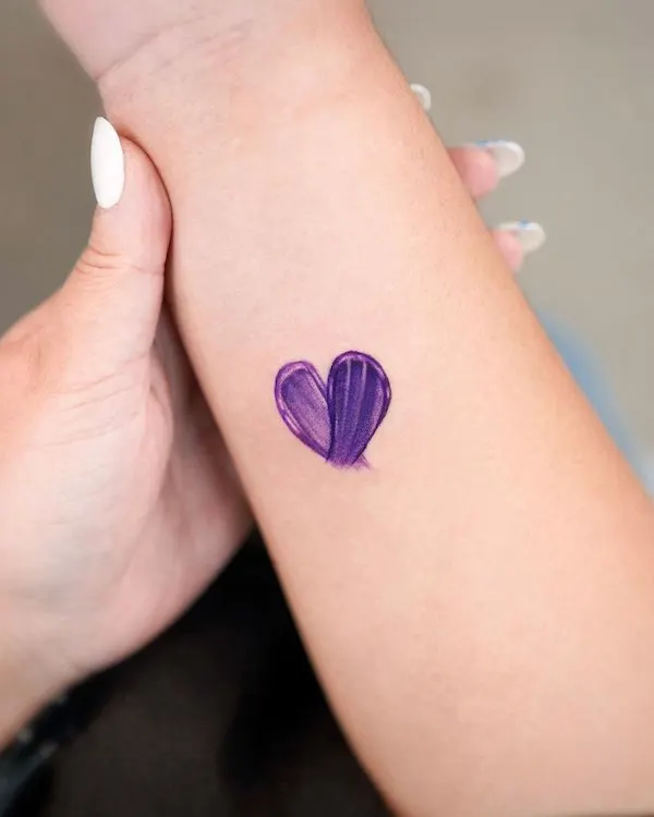 Purple brushstroke heart tattoo on the wrist symbolizing passion, creativity, and emotional depth