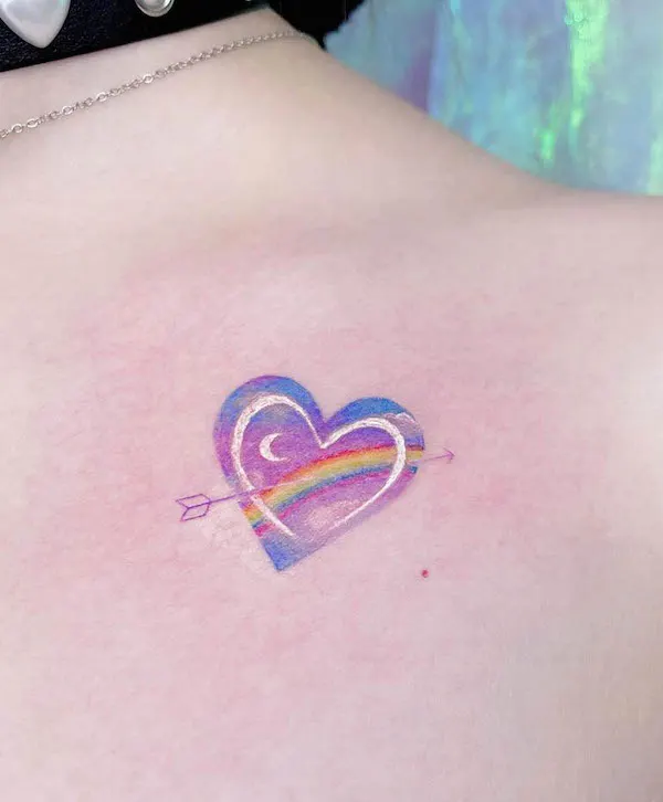 Rainbow heart tattoo with an arrow and crescent moon in soft pastel colors