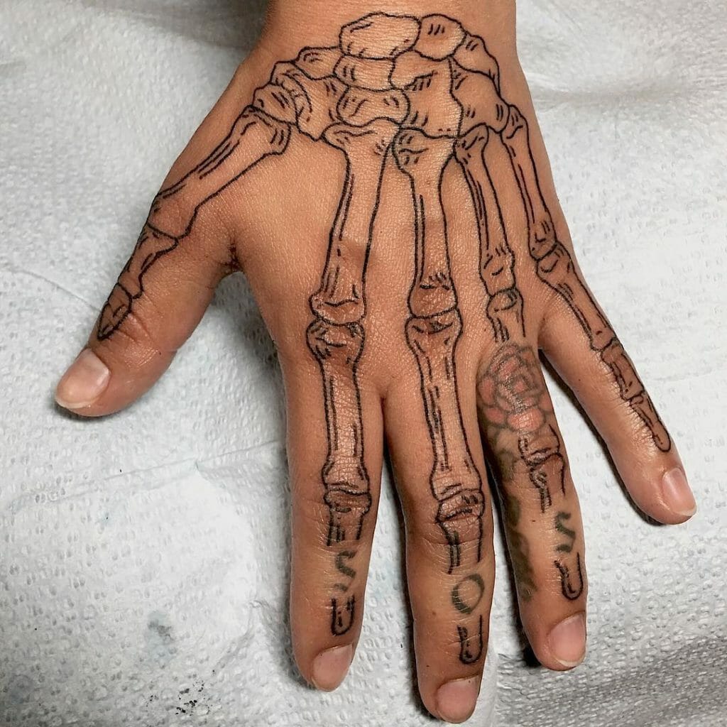 Outlined skeleton hand tattoo with intricate bone details extending over the fingers