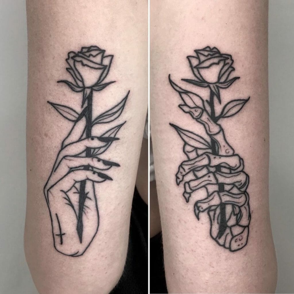 Matching tattoos of a human hand and a skeleton hand holding a rose, symbolizing life and death