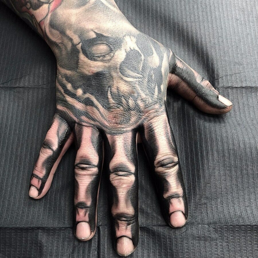 Hyper-realistic skeleton hand tattoo with intricate shading and bone detailing on the hand