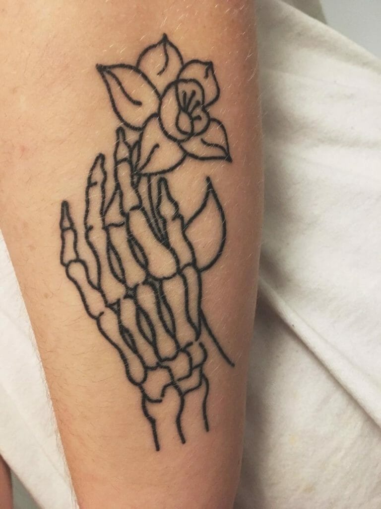 Minimalist skeleton hand tattoo holding a delicate flower outlined in simple black ink