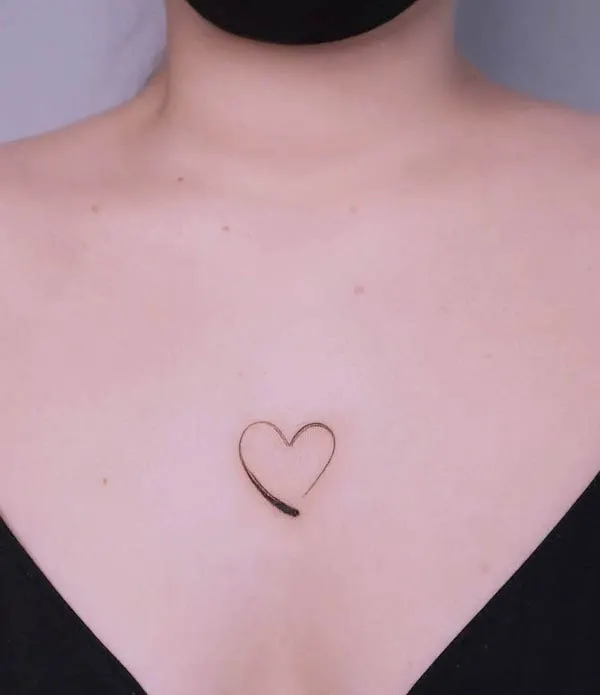 Minimalist heart outline tattoo placed on the collarbone symbolizing love and simplicity