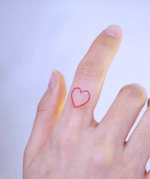 Minimalist red heart tattoo on the finger symbolizing eternal love and commitment