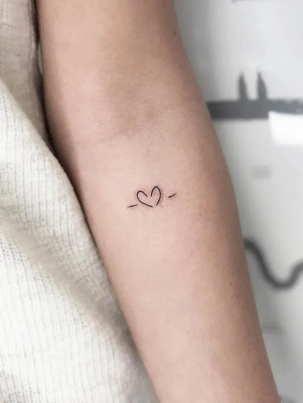 Minimalist heartline tattoo with thin lines extending from both sides of a simple heart