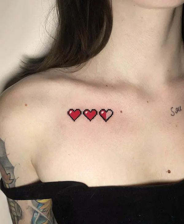 Pixelated hearts tattoo inspired by video game health meter, red hearts on collarbone.