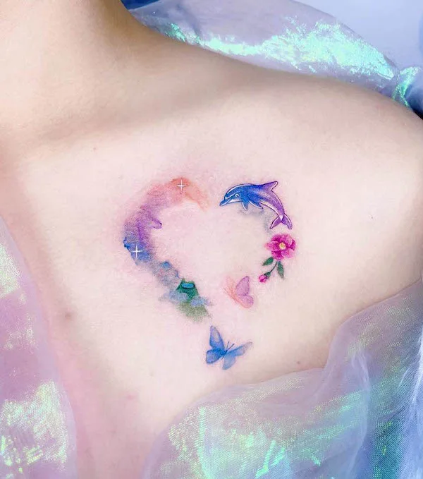 Watercolor heart tattoo with dolphin, butterflies, and flower in pastel colors on upper chest