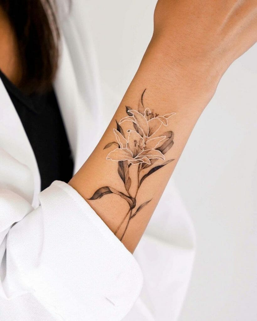 A detailed lily flower tattoo with a combination of white and black ink, featuring soft white petals and dark leaves, placed on the forearm