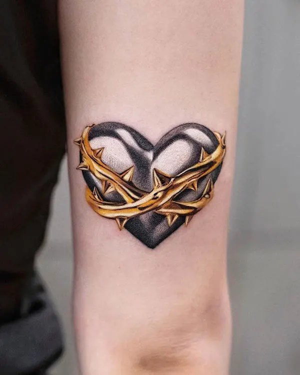 Black heart tattoo with golden crown of thorns symbolizing suffering and endurance