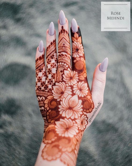 Floral Mehndi design covering the back of the hand with intricate flower motifs and bold geometric detailing on the fingers