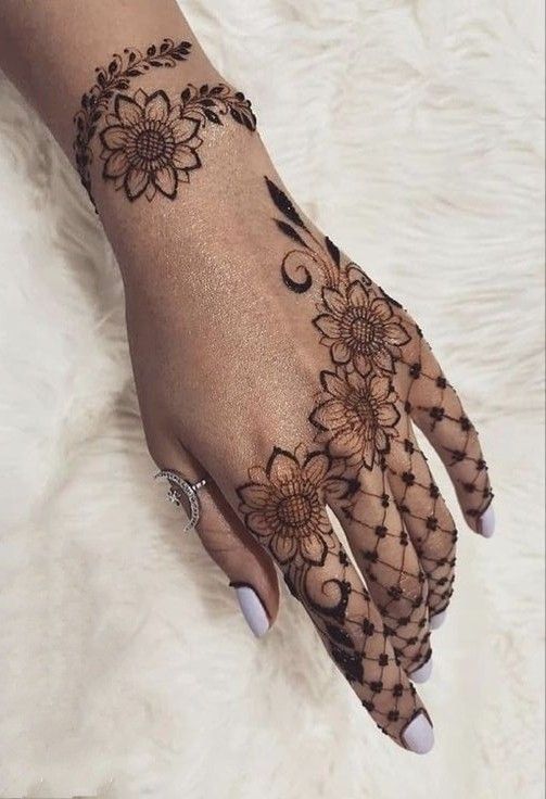 Floral Mehndi design with mesh pattern on the back of the hand, featuring bold flower motifs and fine detailing.