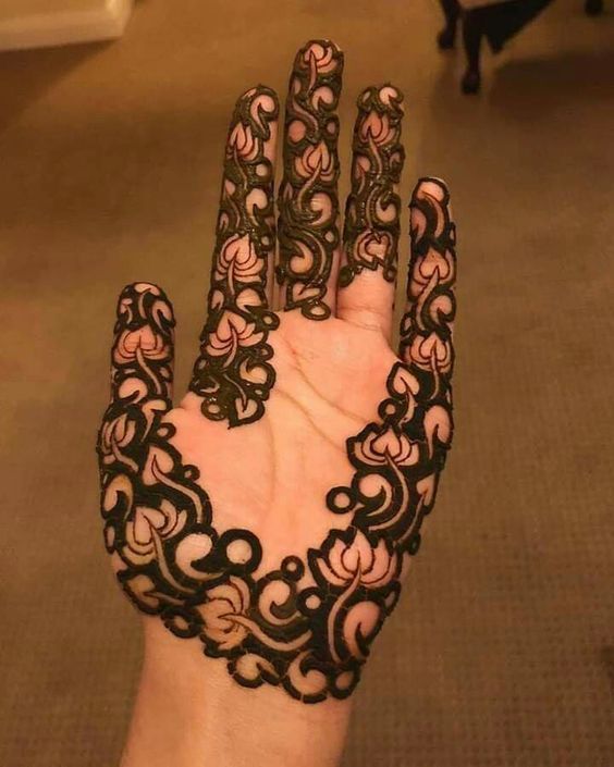 Bold Mehndi design with intricate floral patterns on the palm and fingers, featuring negative space for a modern look