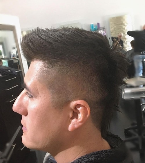 Man with a spiky mullet haircut featuring a high fade and voluminous spiked top