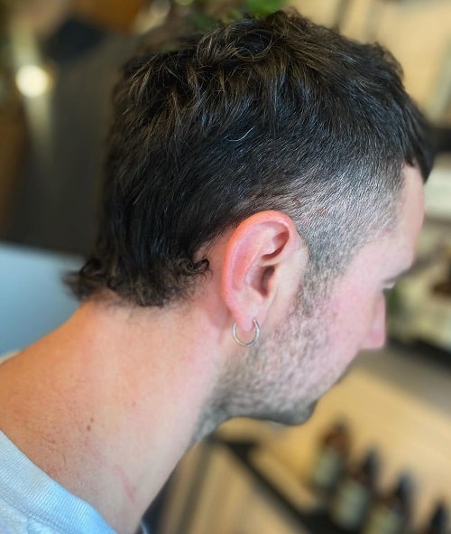 Side view of a man with a curly mullet featuring a clean undercut and subtle texture at the back