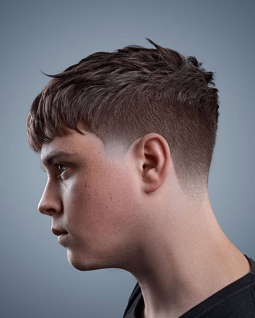 Young man with a textured crew cut hairstyle and a low fade, wearing a black shirt.