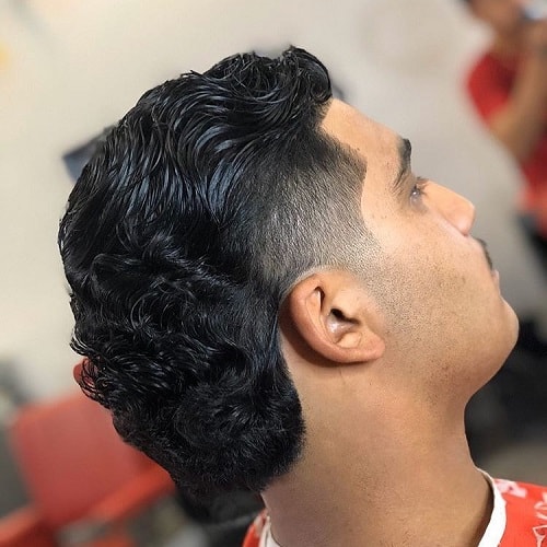 Side view of a man with a classic wavy mullet haircut, featuring a taper fade and styled waves at the back