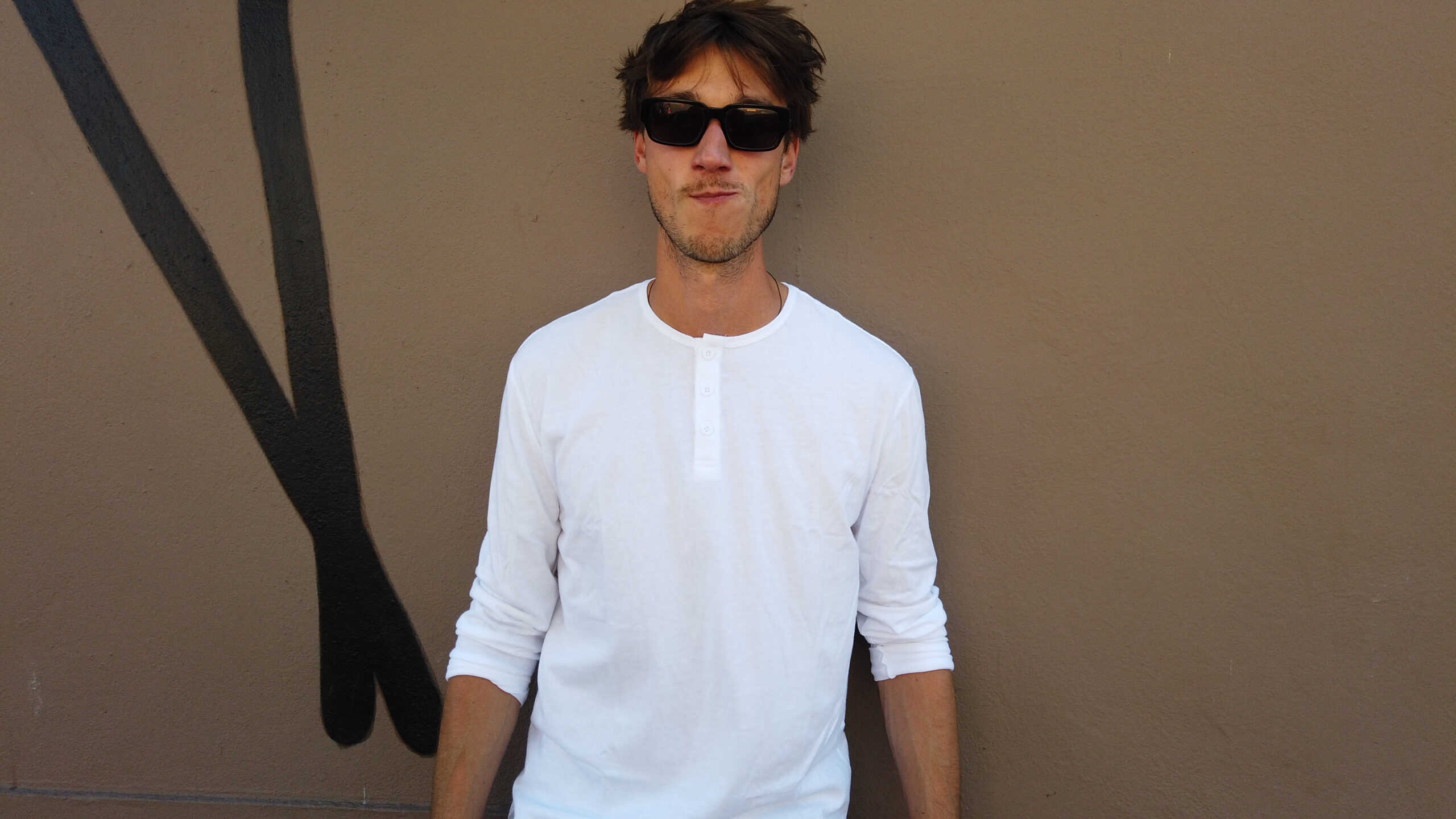 Model wearing the True Classic Tees white long-sleeve Henley shirt, showcasing its tailored fit and minimalist style.