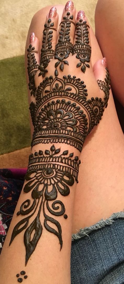 Detailed Mehndi design featuring a mandala pattern on the backhand with intricate floral and leafy motifs extending towards the wrist and fingers