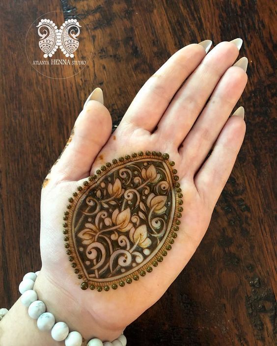 Palm Mehndi design featuring an intricate floral motif enclosed in a bold teardrop-shaped outline, perfect for minimalist occasions