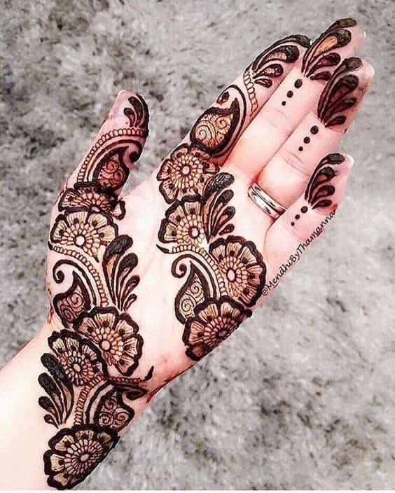 Floral and paisley Mehndi design with bold accents and intricate patterns running along the hand and fingers