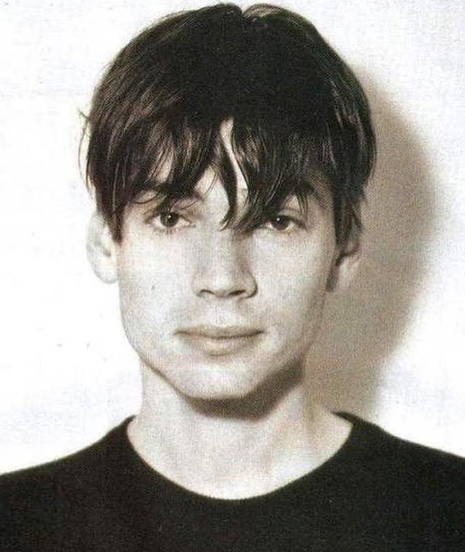 Black and white photo of a young man with a classic 90s Eboy haircut featuring a tousled fringe and subtle middle part.