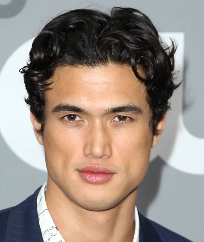 Charles Melton with a short, curly Eboy haircut featuring textured layers and a subtle middle part, wearing a patterned shirt and blazer